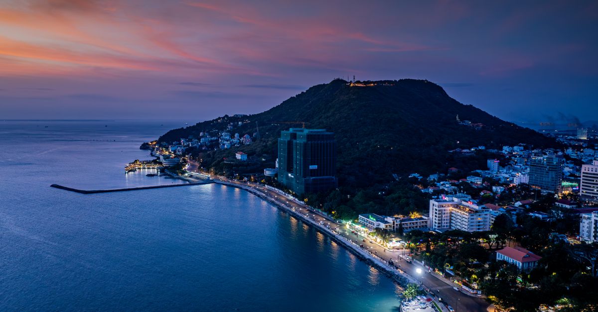Coastal city skyline at dusk with lit buildings along the waterfront