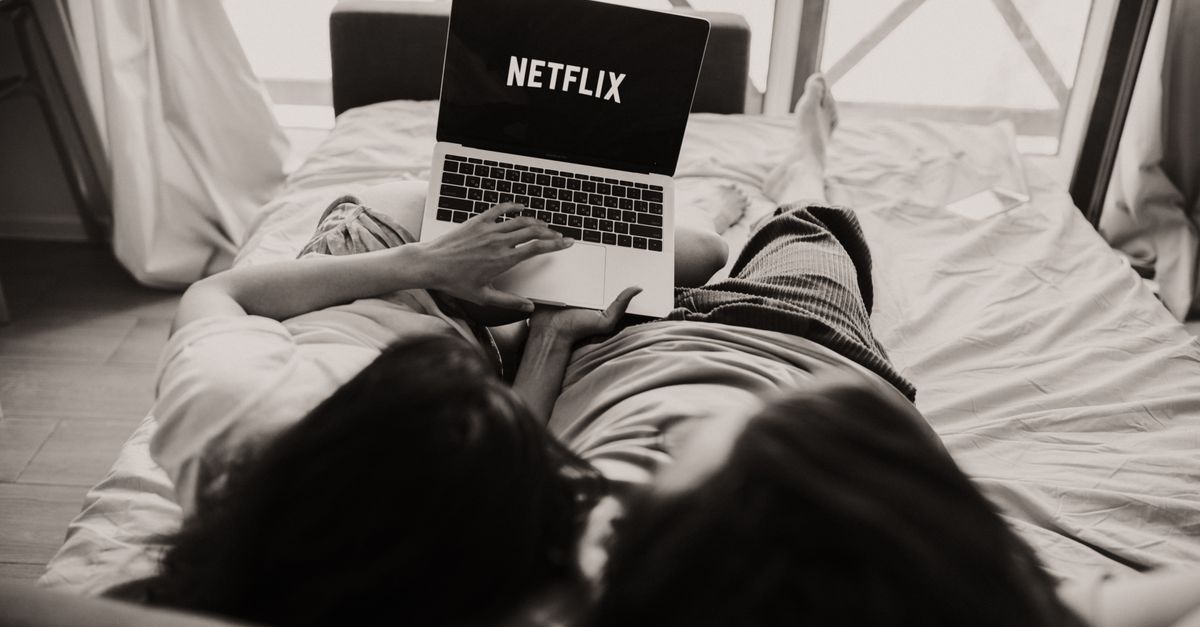 Person watching a streaming series on a laptop in a dim room