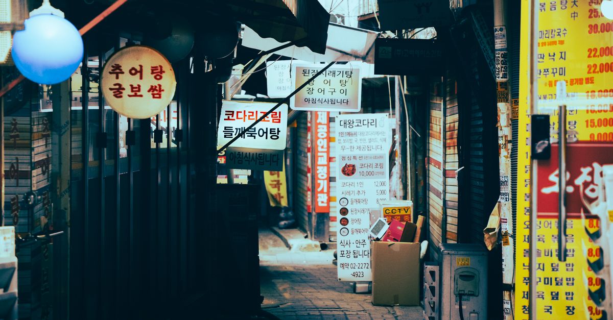 Narrow alley with lit shop signs and small food stalls at night