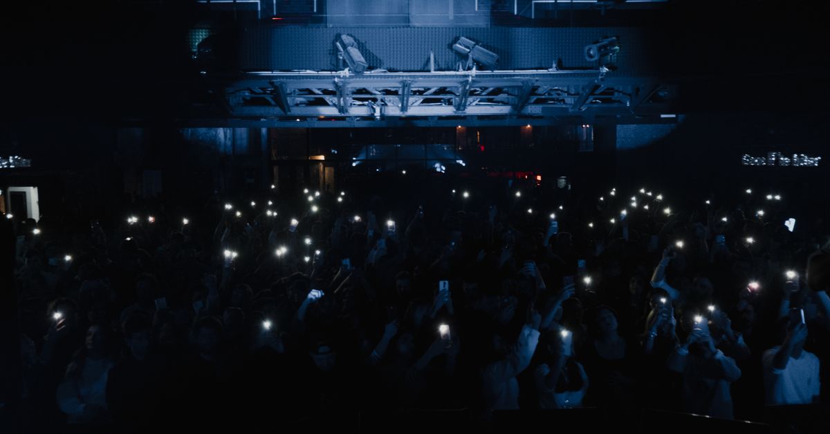 Concert crowd with phone lights raised in a dark venue